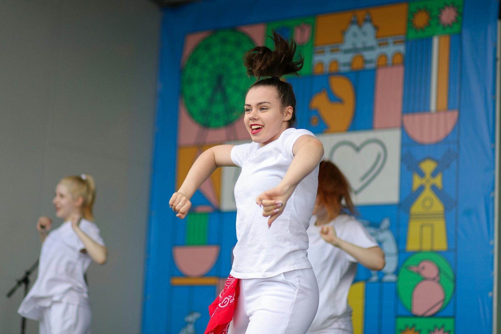 Dynamic programming Young performers joyfully dance on a colorful stage during daytime event.